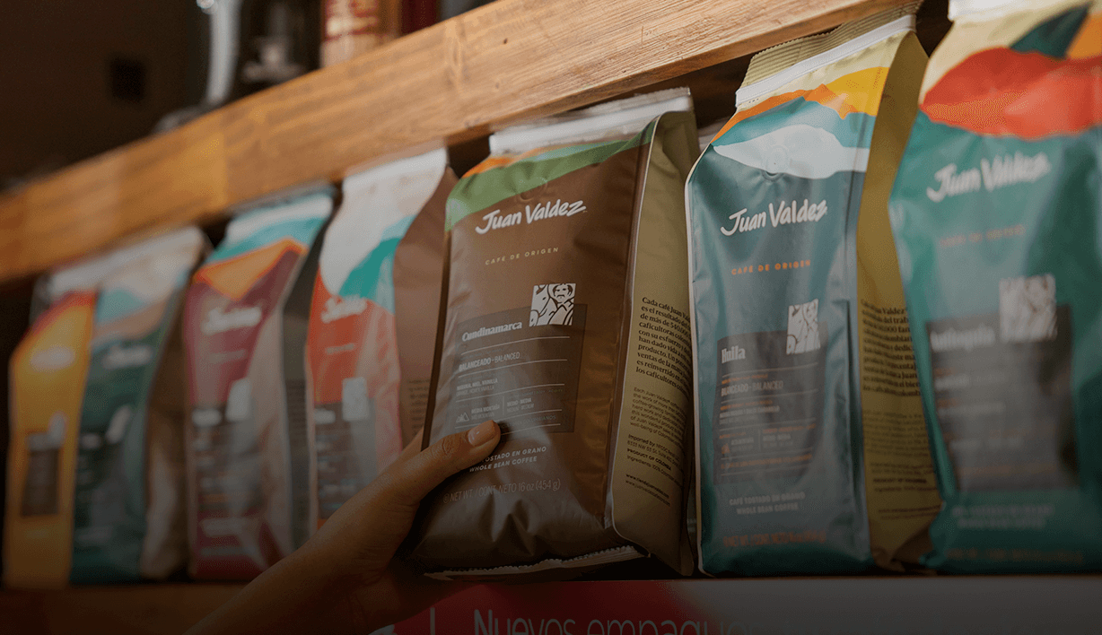Hand taking a bag of Juan Valdez coffee from a shelf of packaged coffee