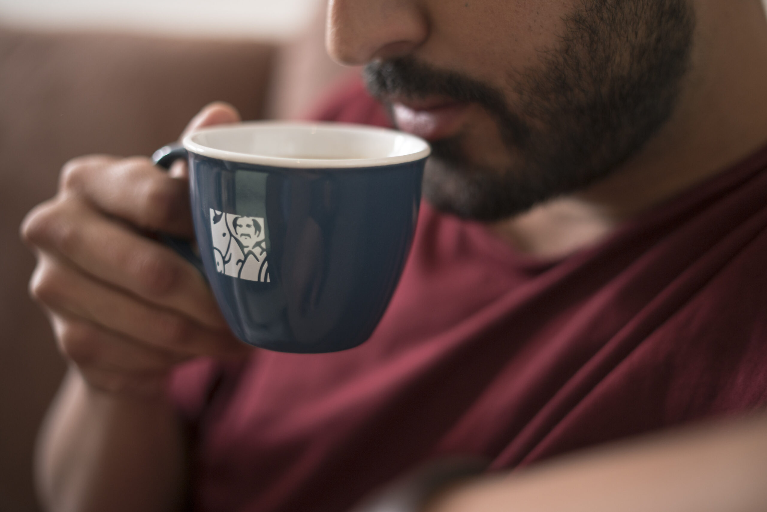 Man drinking coffee from a navy blue Juan Valdez cup
